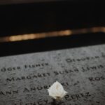 A white rose placed on a memorial monument in New York City, symbolizing remembrance and respect.