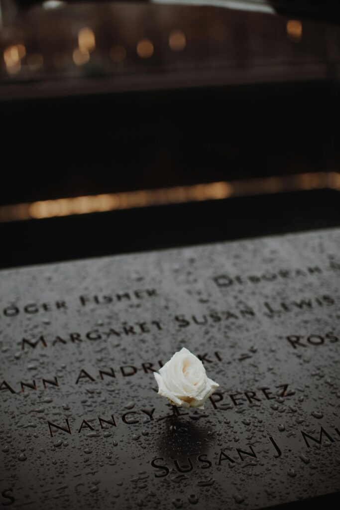 A white rose placed on a memorial monument in New York City, symbolizing remembrance and respect.